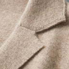 Detail shot of the button fastening and pocket stitching on a grey knitted suit-collar cardigan