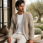 Man wearing a beige knitted blazer cardigan open over a white t-shirt, styled with cream trousers outdoors