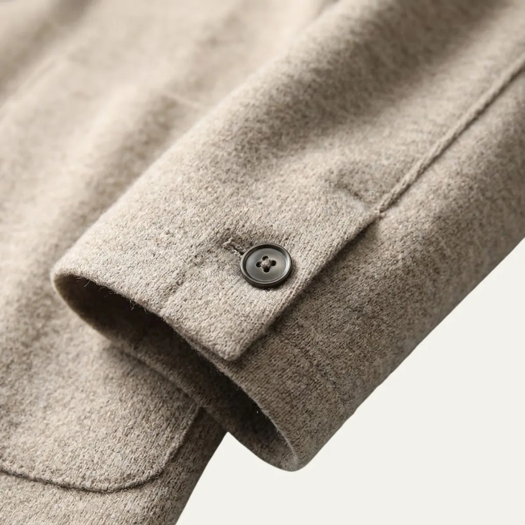 Man adjusting the lapel of a brown knitted blazer cardigan, worn over a white t-shirt