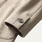 Man adjusting the lapel of a brown knitted blazer cardigan, worn over a white t-shirt