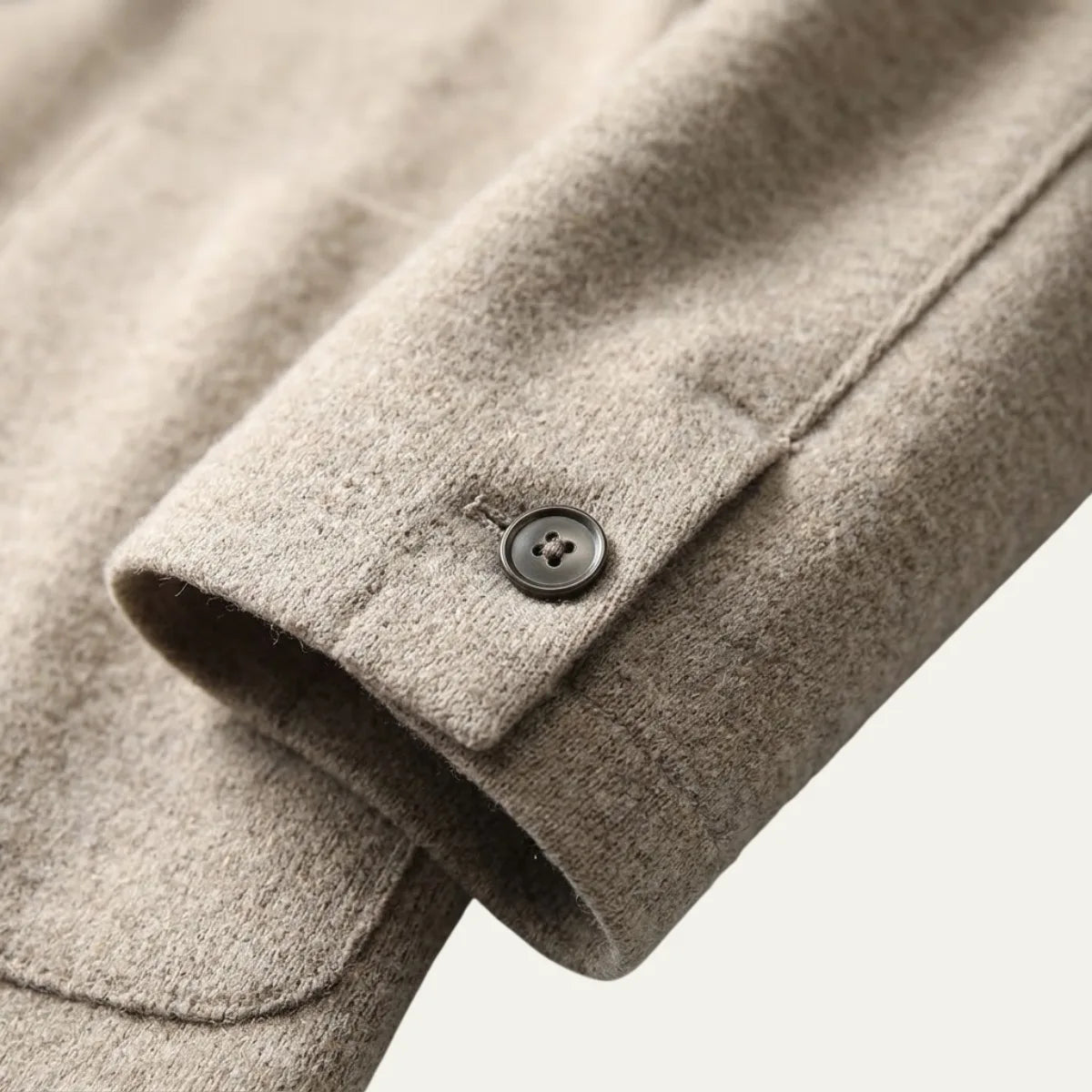 Man adjusting the lapel of a brown knitted blazer cardigan, worn over a white t-shirt