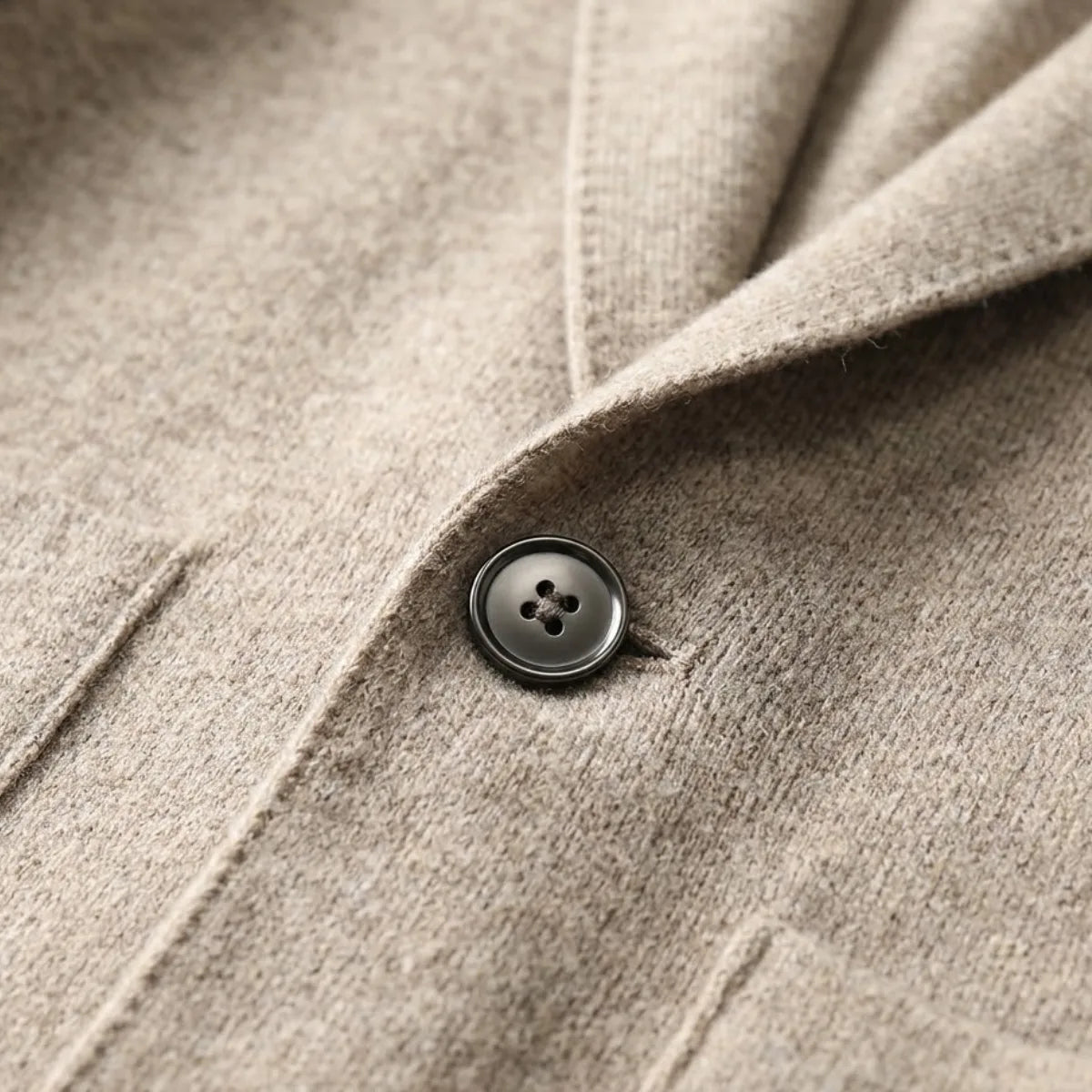 Grey knitted blazer cardigan on a hanger, three-quarter view showing collar shape and overall silhouette