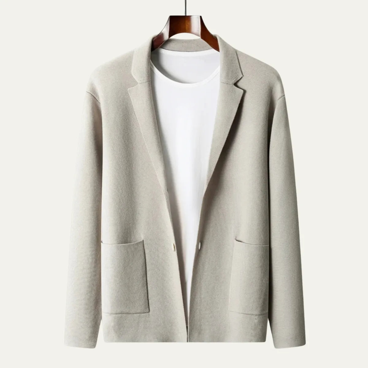 Light grey knitted blazer cardigan on a wooden hanger, showing the soft collar and two front patch pockets