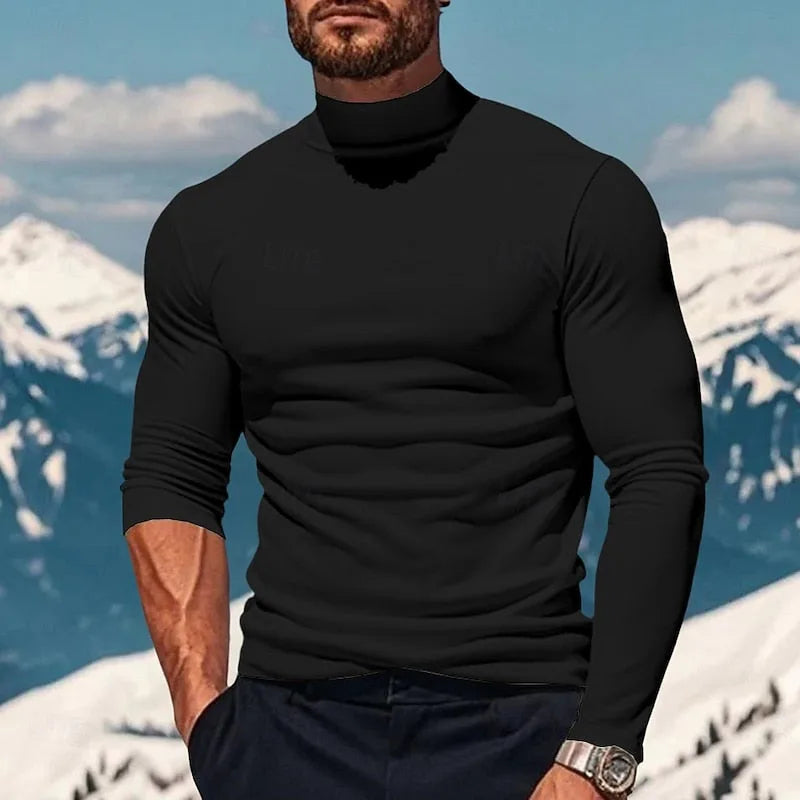 Close-up front view of a man wearing a black mock neck long sleeve top against a snowy mountain backdrop
