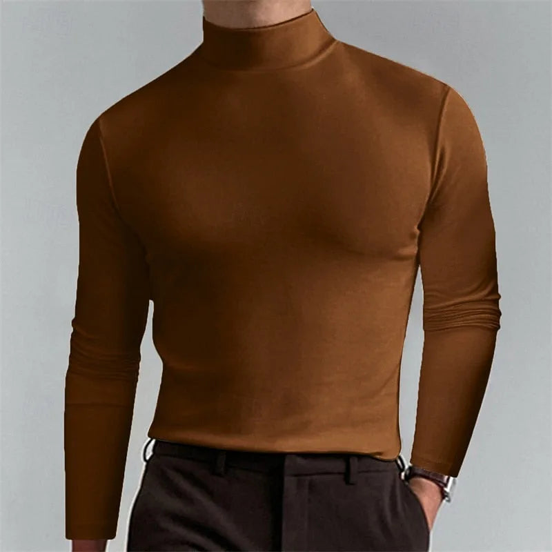 Front view of man wearing a warm brown mock-neck jumper with long fitted sleeves, paired with dark trousers