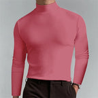 Coral pink mock-neck top worn with dark trousers, showing the fitted long sleeves and ribbed collar