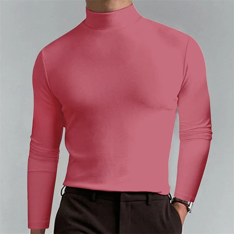 Coral pink mock-neck top worn with dark trousers, showing the fitted long sleeves and ribbed collar