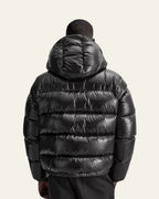 Back view of a man wearing the black puffer jacket showing the hood and quilted back panel