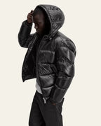 Side profile of a man adjusting his hair while wearing the black hooded puffer jacket