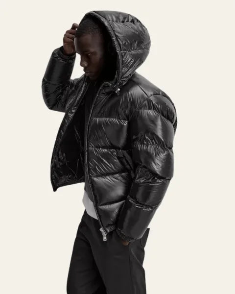 Side profile of a man adjusting his hair while wearing the black hooded puffer jacket