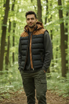 Front view of the padded gilet worn over a grey jumper, showing the tan quilted shoulder panels and zip pockets.