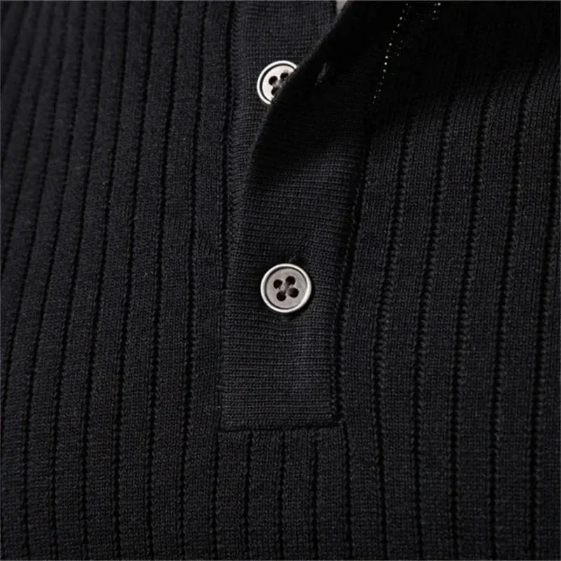 Man wearing a black ribbed henley jumper against a grey studio background, front facing