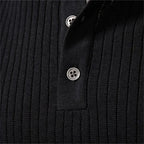 Man wearing a black ribbed henley jumper against a grey studio background, front facing