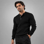 Man wearing a black ribbed henley jumper with buttoned collar, styled with black trousers
