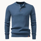 Flat view of a slate blue ribbed knit henley jumper with button placket and leather logo patch