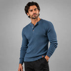 Man wearing a slate blue ribbed henley jumper with hand in pocket, paired with black trousers
