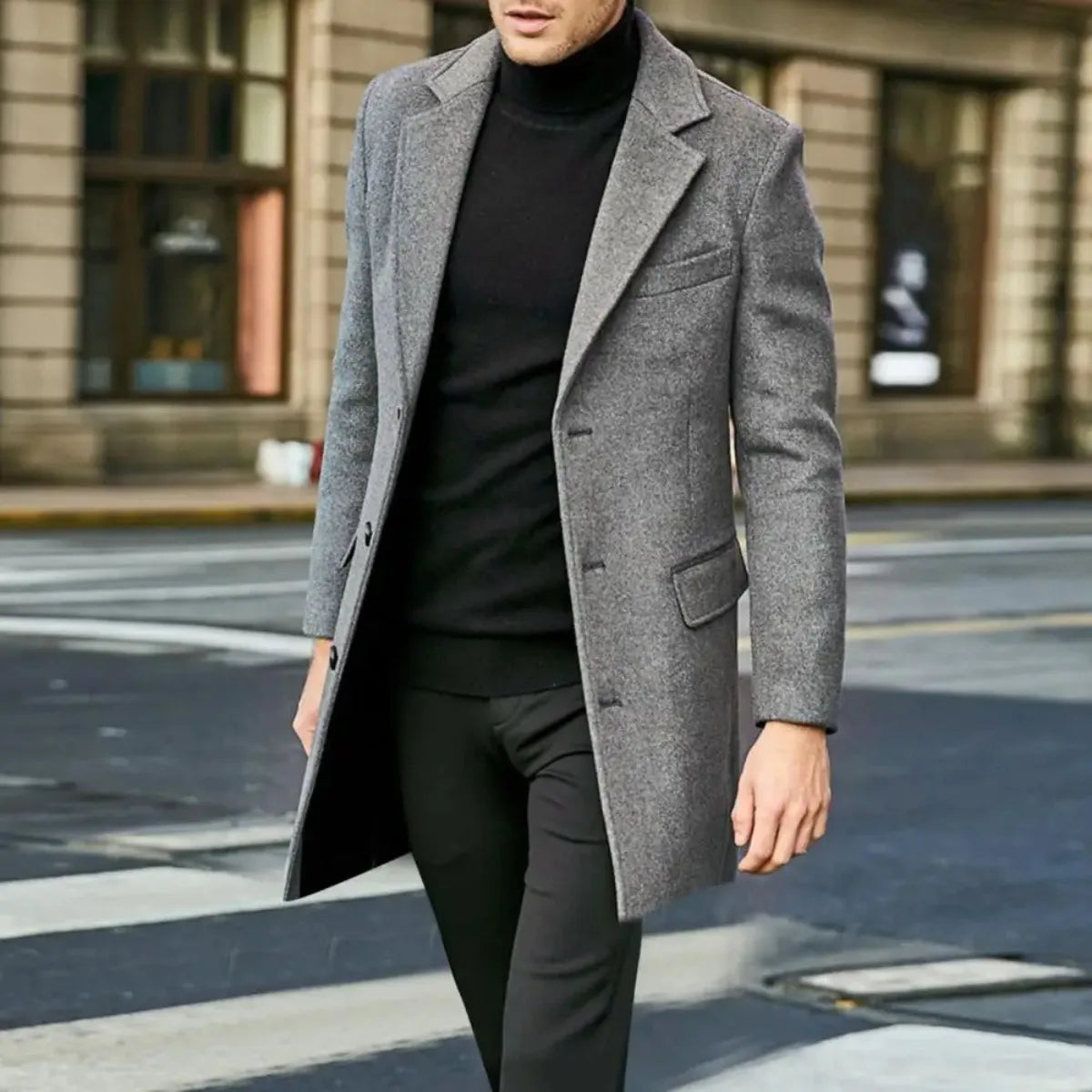 Side view of a man walking outdoors in a grey wool overcoat over a black polo neck jumper