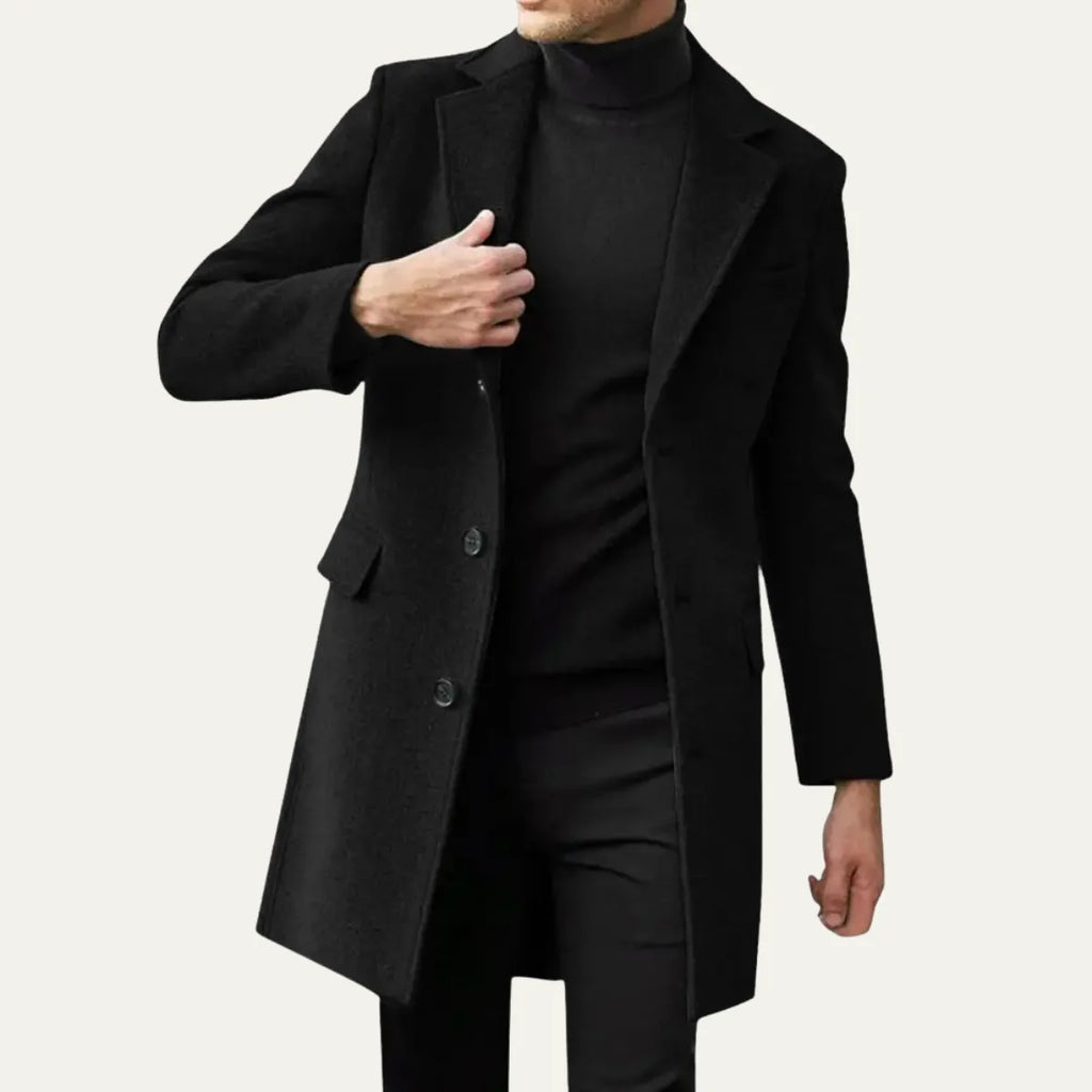 Man wearing a black single-breasted overcoat over a black polo neck, buttoned at the front
