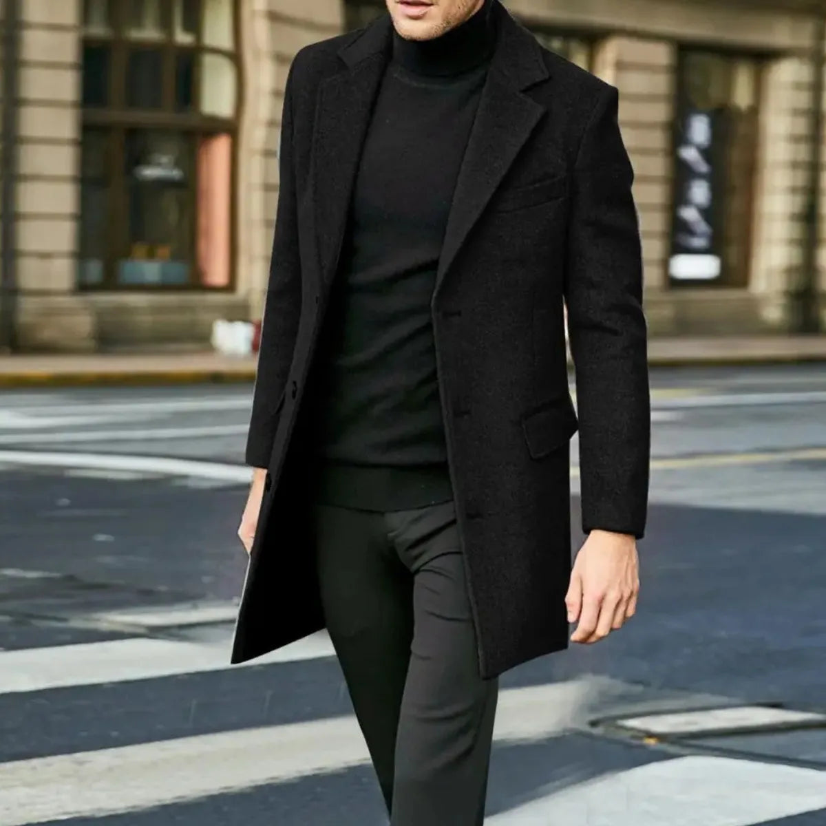 Man walking on a city street wearing an open black wool overcoat over black trousers