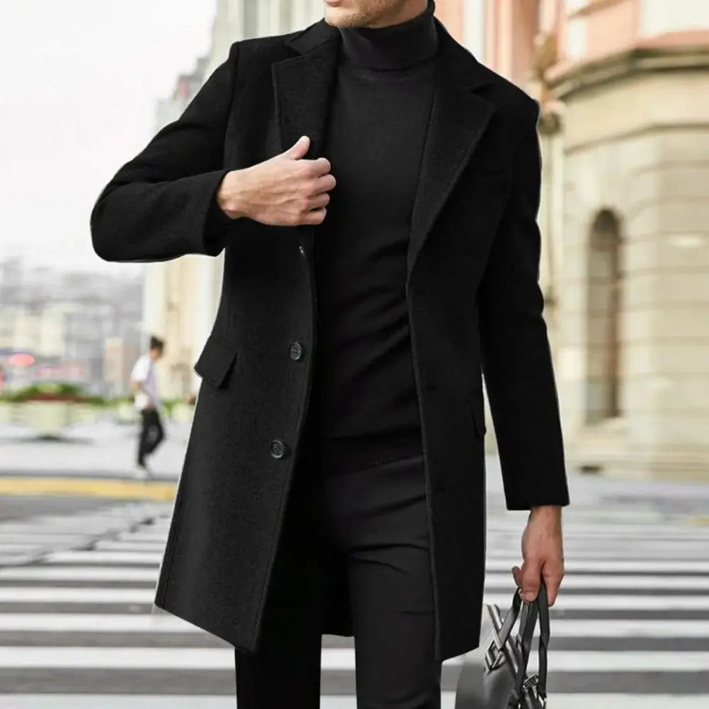 Close-up of a man adjusting the lapel of a black wool overcoat, holding a bag, street background