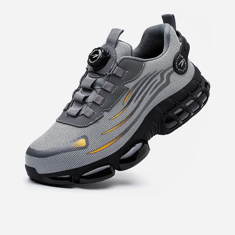 Angled front view of grey mesh trainer with black chunky sole, dial lacing system and orange accent details
