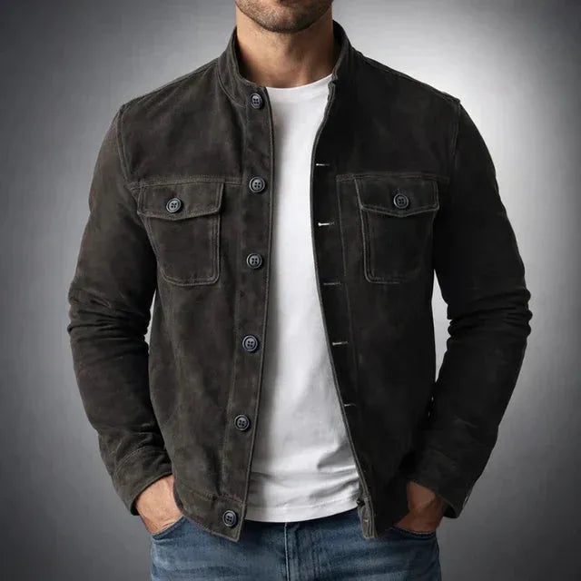 Man in a dark grey-brown suede jacket, fully buttoned, showing the tailored fit and flap pocket detail