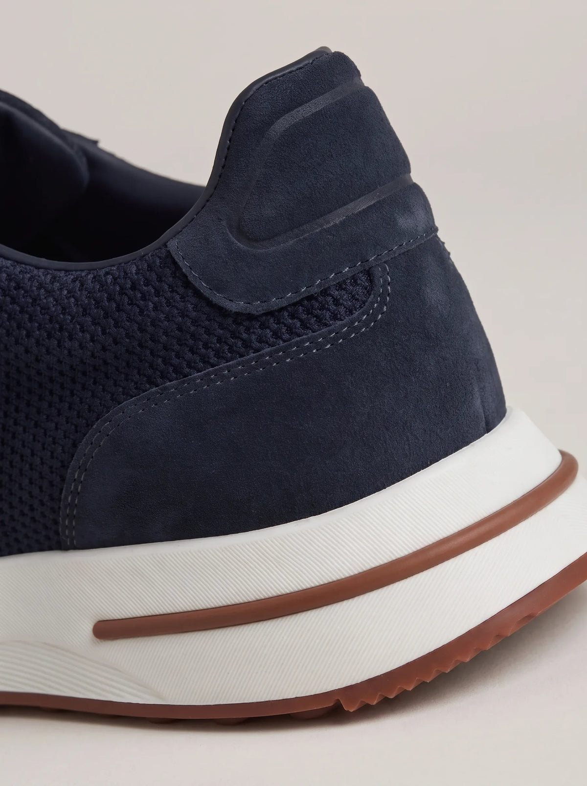 Close-up of the navy suede heel panel showing ribbed overlay stitching above a white and brown midsole
