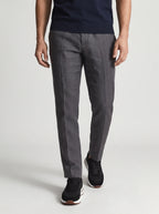 Man walking in grey linen trousers wearing black suede trainers with white midsole and brown trim