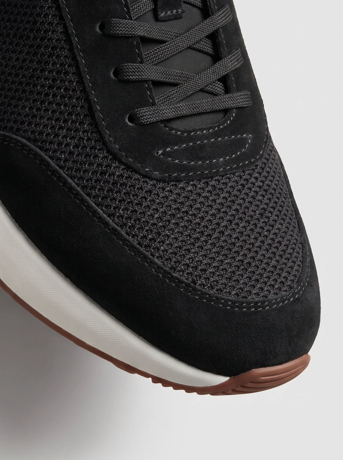 Close-up of the black suede toe cap and mesh upper showing contrast stitching and lace detail