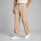 Front view of man wearing beige pleated straight-leg trousers with white trainers and cream polo
