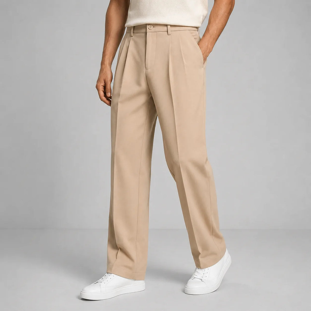 Front view of man wearing beige pleated straight-leg trousers with white trainers and cream polo