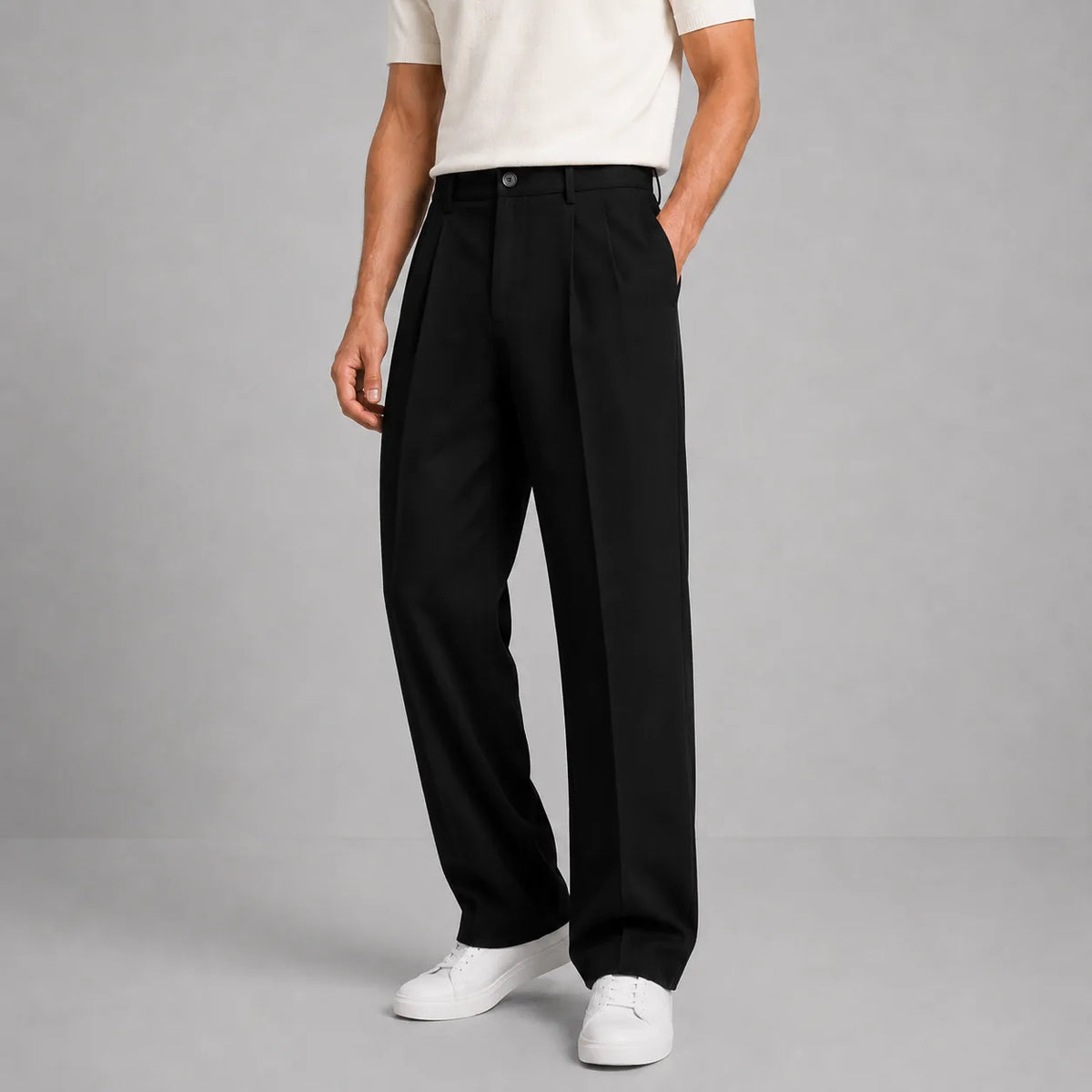 Front view of black pleated tailored trousers styled with a cream knit top and white trainers