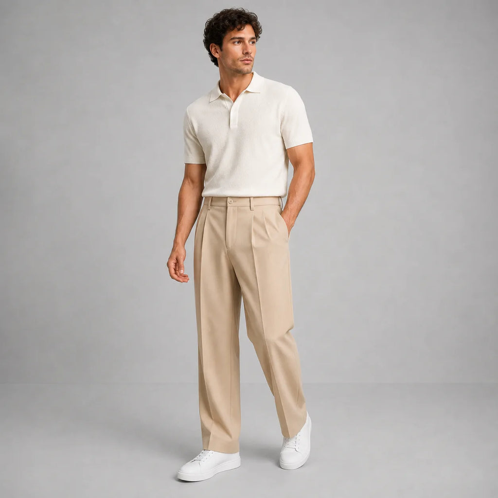 Full-length front view of model wearing beige pleated trousers with a cream knitted polo shirt