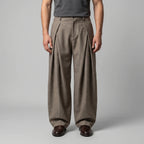 Front view of beige wide-leg tailored trousers with deep front pleats, styled with a grey tank top
