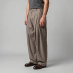 Side angle of the beige trousers showing the full, flowing leg shape and tapered hem