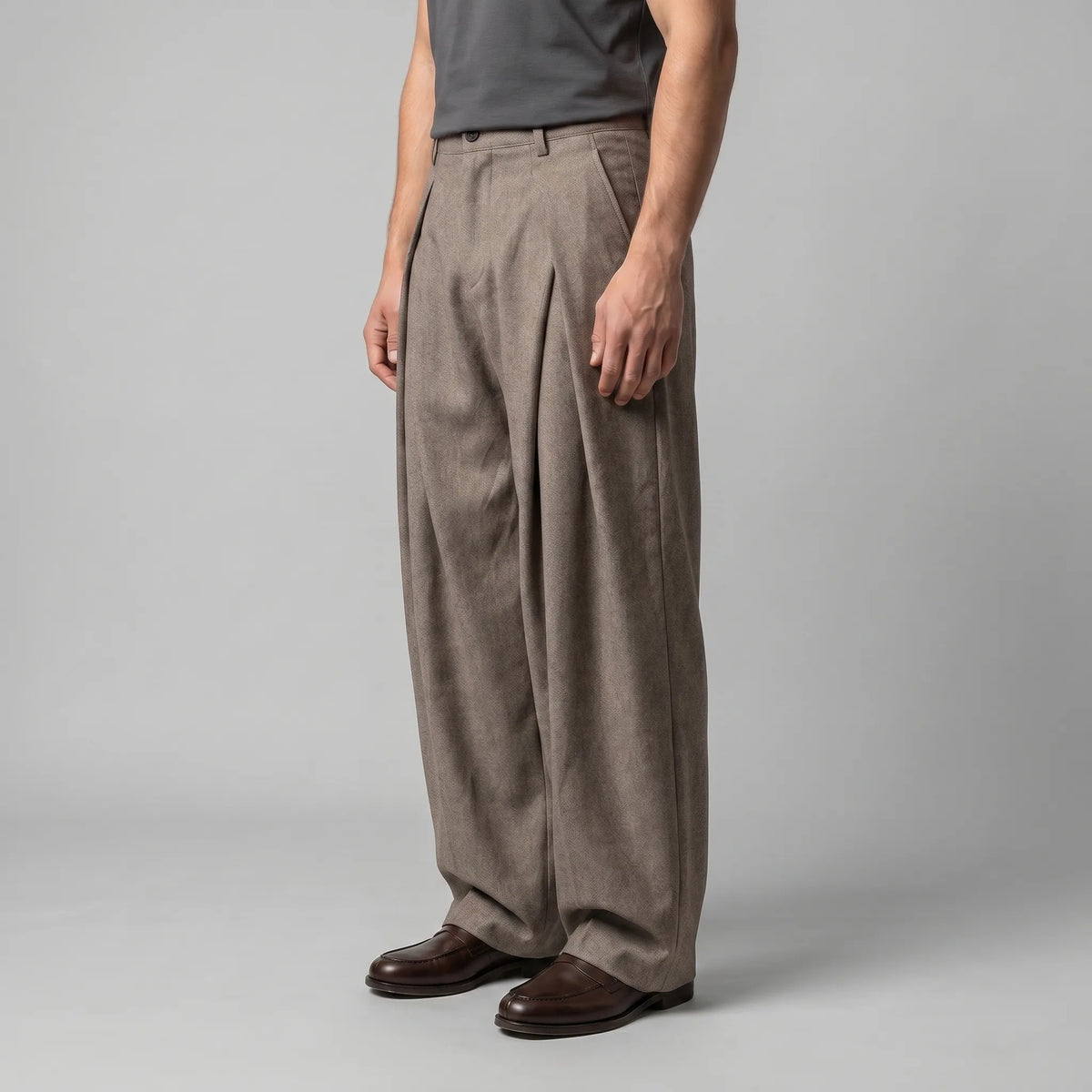 Side angle of the beige trousers showing the full, flowing leg shape and tapered hem