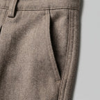 Close-up of the front pleat and pocket construction on the textured beige fabric