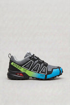 Side view of grey trainer with black overlays, neon green gradient panel and blue heel detail reading Speed and Keep Running