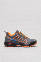 Side view of grey trainer with bold orange outlined panels, orange laces and orange accented sole