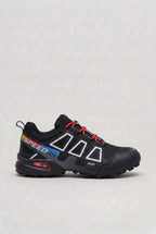 Side profile of black trainer with red, yellow and blue striped Speed branding and red laces