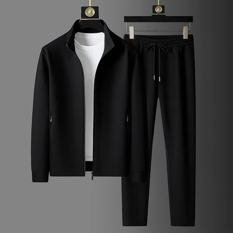 Black zip-up tracksuit jacket with white t-shirt layered underneath and matching tapered joggers on hangers
