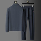 Rear view of grey tracksuit jacket and joggers showing back yoke seam and pocket with striped tab detail
