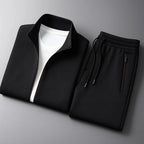 Folded black tracksuit jacket and joggers laid flat showing zip pocket, drawstring cords and stand collar