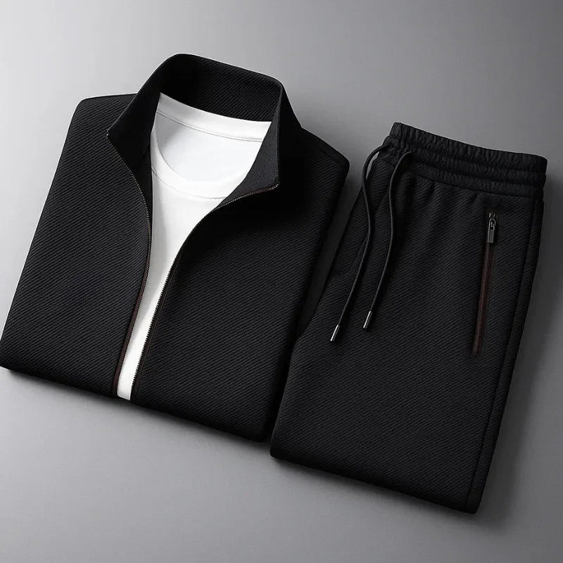 Folded black tracksuit jacket and joggers laid flat showing zip pocket, drawstring cords and stand collar