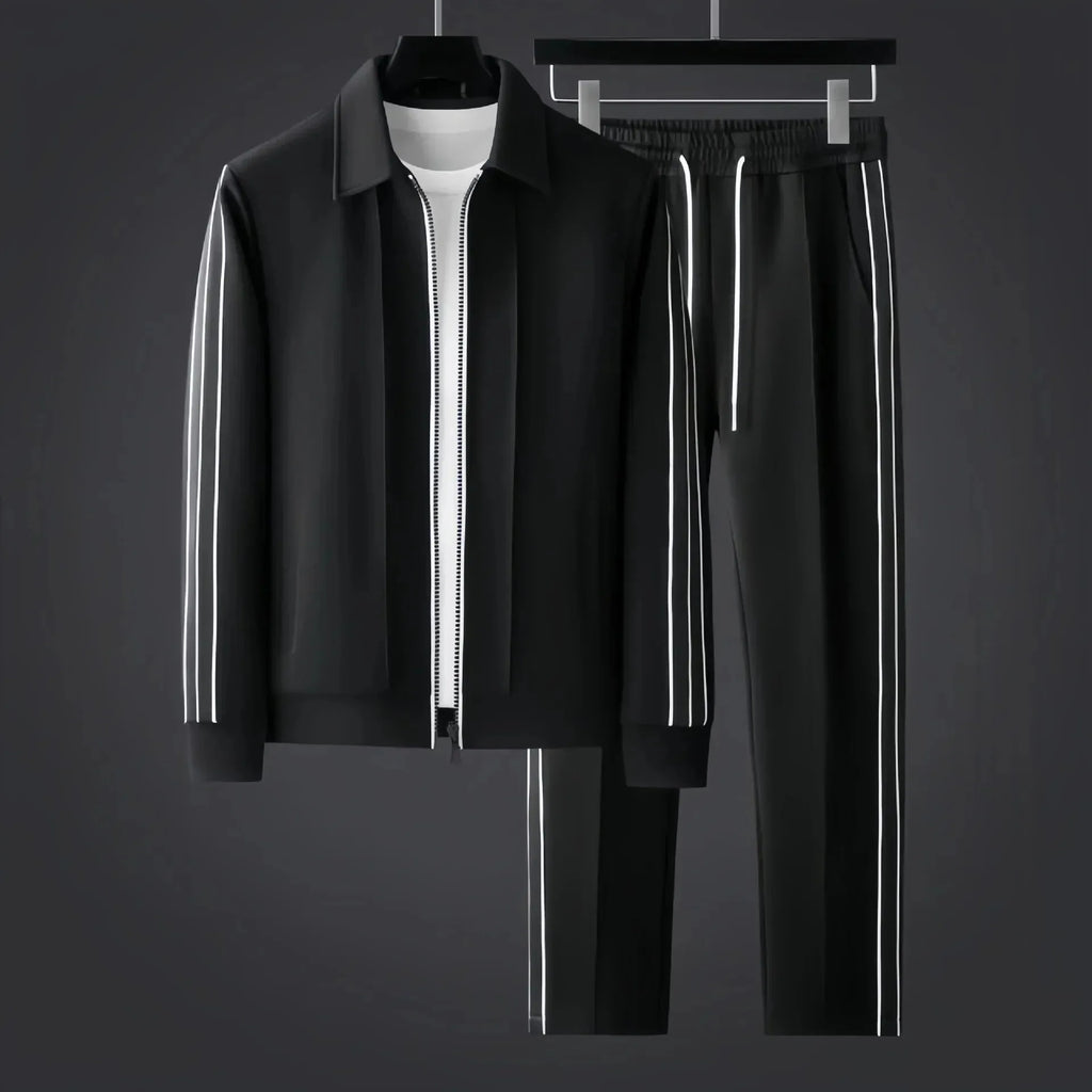 Black zip-up tracksuit jacket and trousers with white side stripes displayed on hangers against a dark grey backdrop