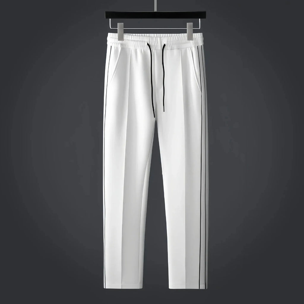 White tapered track trousers with drawstring waist, side pockets and thin black side stripes