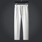 White tapered track trousers with drawstring waist, side pockets and thin black side stripes