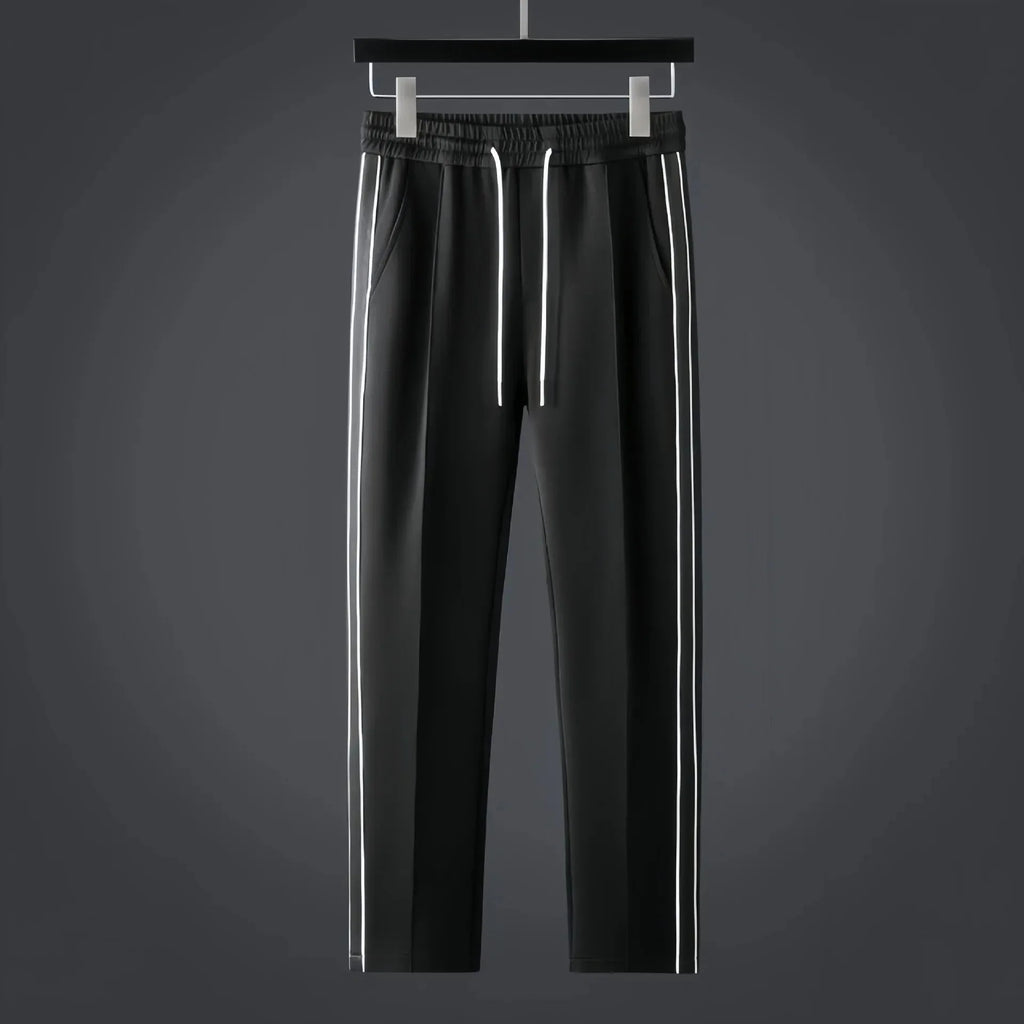 Black tapered track trousers with elastic drawstring waist and white side stripes running down each leg