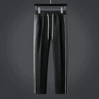 Black tapered track trousers with elastic drawstring waist and white side stripes running down each leg
