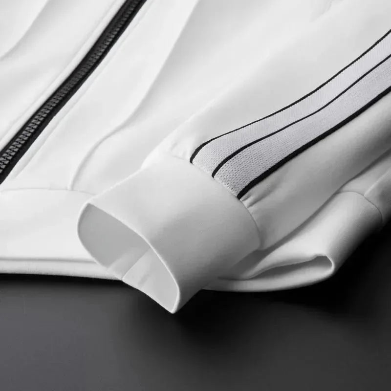 Close-up of the white track jacket showing the zip closure, ribbed cuff and twin-stripe sleeve detail